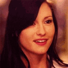 a close up of a woman 's face with long black hair and red lipstick .