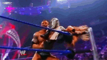 two wrestlers are fighting in a wrestling ring with a crowd watching .