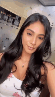 a woman with long black hair is taking a selfie in a room .