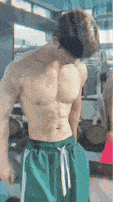 a shirtless man in green shorts is lifting weights in a gym .