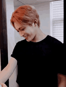 a man with red hair wearing a black shirt is smiling