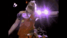 a man is standing on a stage with his arms outstretched and a purple light behind him .