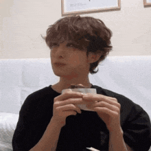 a young man with curly hair is sitting on a couch eating a piece of cake .