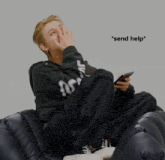 a person sitting on a couch with a cell phone and the words * send help * on the bottom