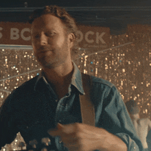 a man in a denim shirt stands in front of a sign that says bc rock