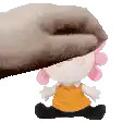 a hand is petting a stuffed doll with pink hair and a yellow shirt .