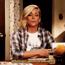 a woman in a plaid shirt is sitting at a table and says whatever mom it worked .