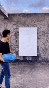 a man is holding a blue frisbee in front of a white board on a wall .