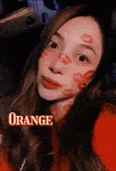 a woman with kisses on her face and the word orange in the corner