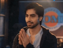 a man with a beard is clapping his hands in front of a sign that says bombay oil .