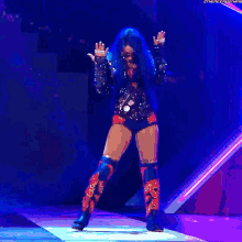 a woman with blue hair is dancing on a stage with the words the next thing written on the bottom