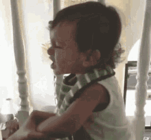 a baby is crying while wearing a bib and sitting on a chair .