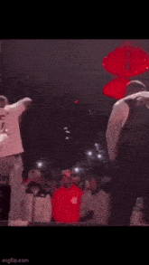 a man in a white shirt is standing on a stage with a crowd watching .