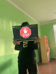 a person is holding a laptop with a stop sign on it