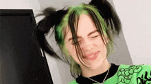 billie eilish is wearing a green shirt and has green hair .