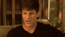 a young man is sitting on a couch and making a funny face