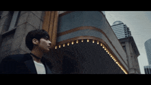 a man standing in front of a building with lights on