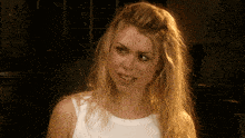 a woman with blonde hair and a white shirt smiles