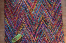 a pair of green slippers sit on a colorful rug with a chevron pattern