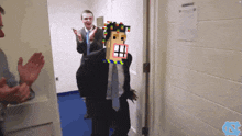 a man in a suit and tie stands in a hallway with a schedule on the wall behind him