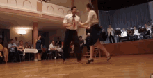 a man and a woman are dancing on a dance floor in front of a crowd
