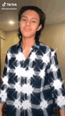 a young man wearing a plaid shirt has a tiktok watermark on his shirt