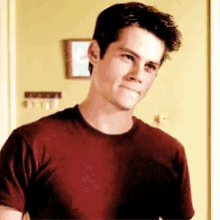 a young man wearing a maroon shirt is standing in front of a yellow wall .