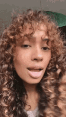 a woman with curly hair is making a funny face and looking at the camera .