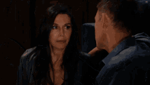 a man in a blue shirt looks at a woman in a gray dress