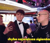 a man in a tuxedo is being interviewed by another man with the words " chyba najwieksza sigiemka " in yellow