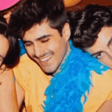 a man with a blue feather boa around his neck smiles for the camera