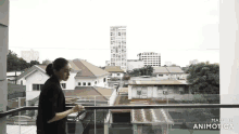 a woman is standing on a balcony with the words made in animatica on the bottom