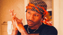 a man wearing a bandana is washing his hands in a bathroom .