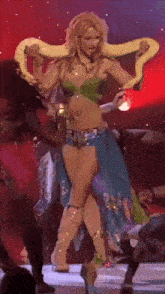 a woman in a green top and blue skirt is holding a snake