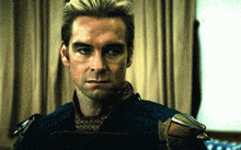a man in a superhero costume is looking at the camera in a dark room .