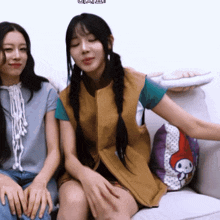 two girls are sitting on a couch with a pillow that says my melody on it