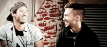 two men are sitting next to each other and laughing .