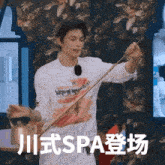 a man wearing a white shirt with a picture of teeth is holding a stick in front of the word spa