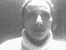 a black and white photo of a woman wearing a white turtleneck sweater .