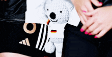 a person holding a stuffed koala bear with a german flag on it