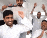 a group of men in white shirts are dancing together