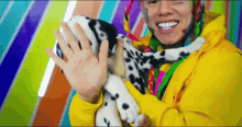a man in a yellow jacket is holding a dalmatian puppy and smiling .