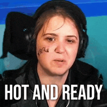 a woman with a tattoo on her face is wearing headphones and has the words hot and ready on her face .