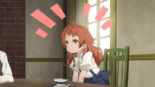 a girl with red hair sits at a table with a cup of coffee