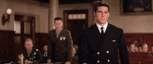 a man in a navy uniform stands in front of a group of men
