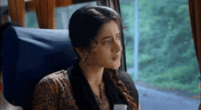 a woman is sitting on a bus looking out the window and crying .