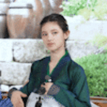 a woman in a green kimono is holding a bag and a bottle .