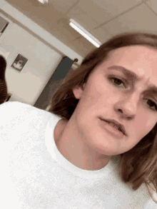 a woman with long hair is wearing a white sweater and making a funny face