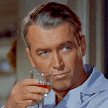 a man in a blue shirt is holding a wine glass
