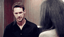 a man in a black shirt is standing next to a woman in a room .